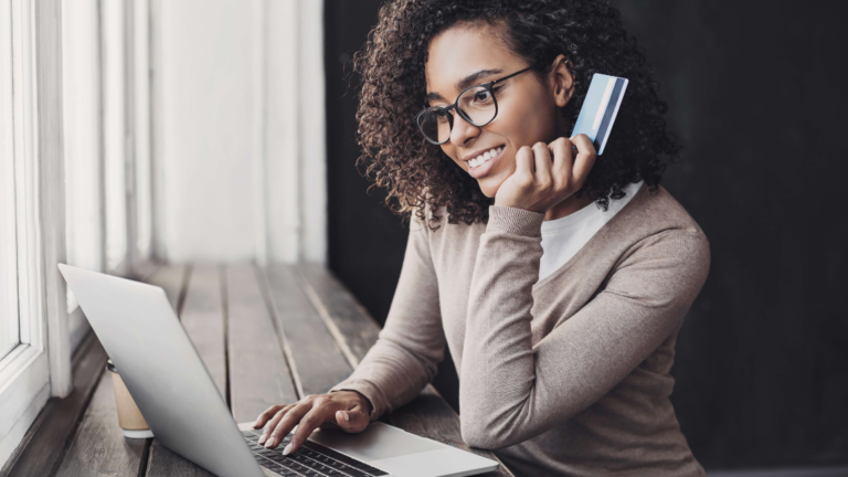 Woman on laptop with payment card in her hand