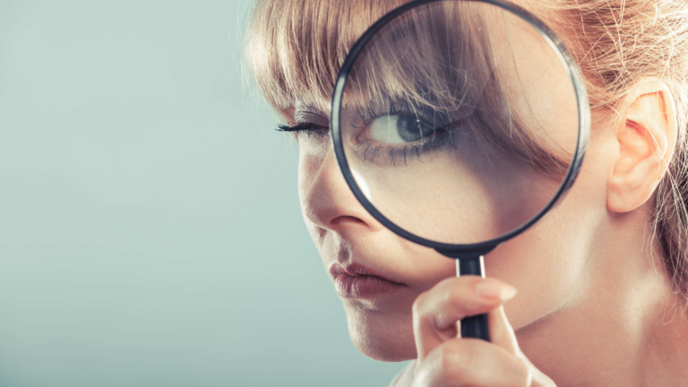 Woman looking through magnifying glass to symbolise screening clients