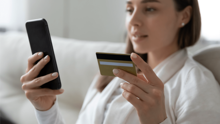 Woman holding bank card and phone about to make a payment online