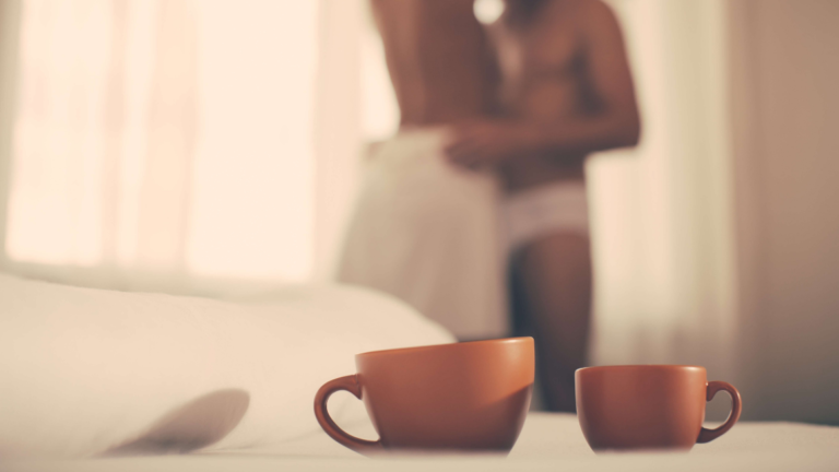 Cups of coffee on bed and couple having morning sex in bedroom