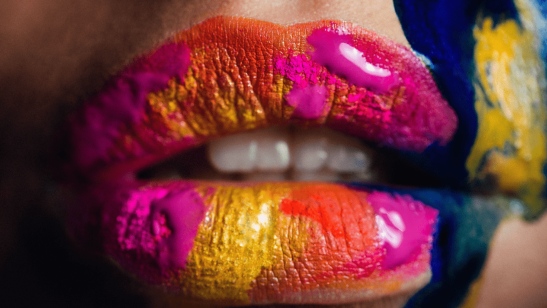 Woman's lips soaked in different rainbow coloured paints