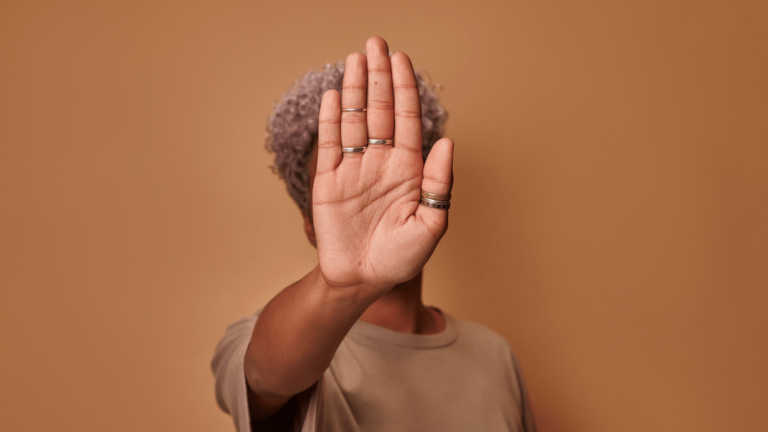 frican American woman covers herself with her palm, confidently shows prohibitory gesture stop and no signs shakes her head