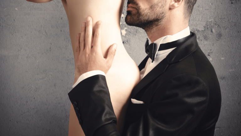 man in a tuxedo on his knees holding a naked woman