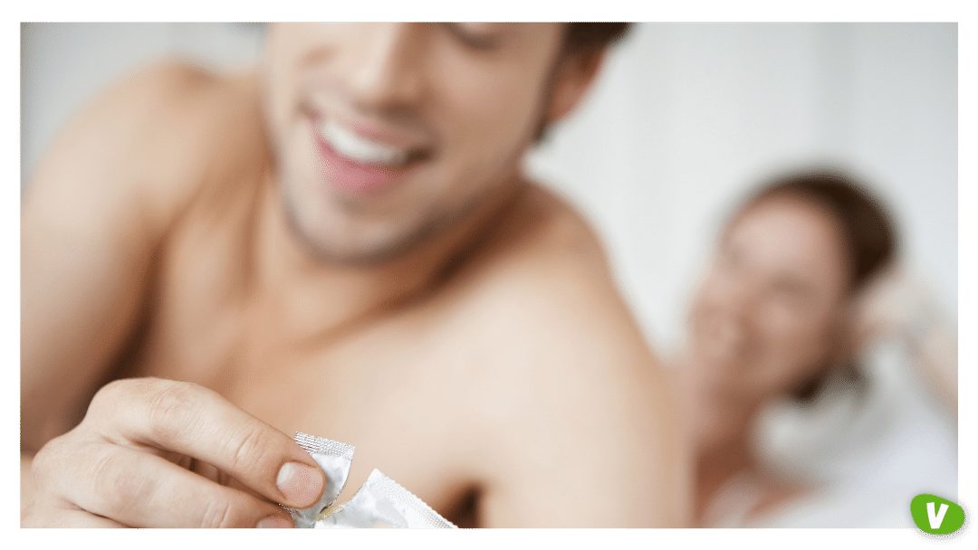 man opening condom with woman in bed. safe sex concept