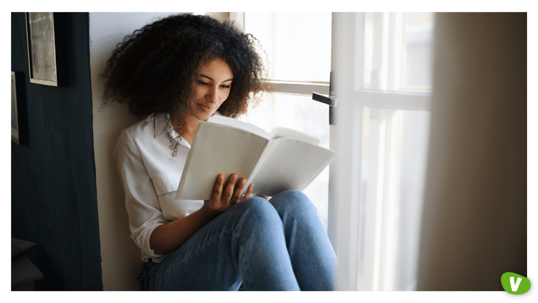 portrait of young woman with book indoors at home, reading