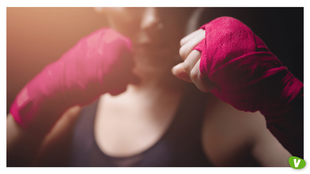 close-up of MMA Girl holding fists pink boxing bandages to protect her fingers in fight, concept women self-defence