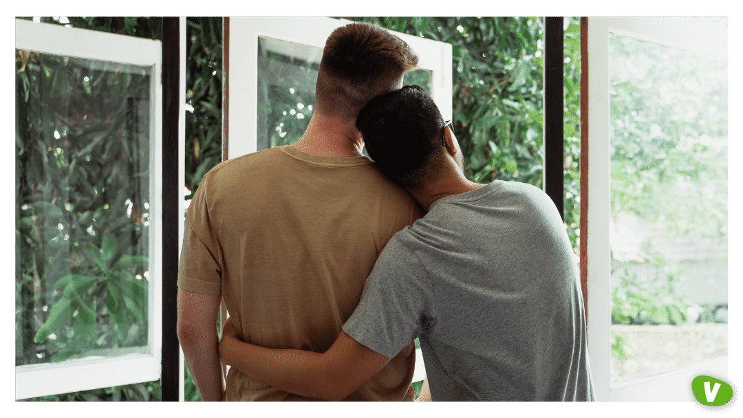 gay couple in embrace looking out the window
