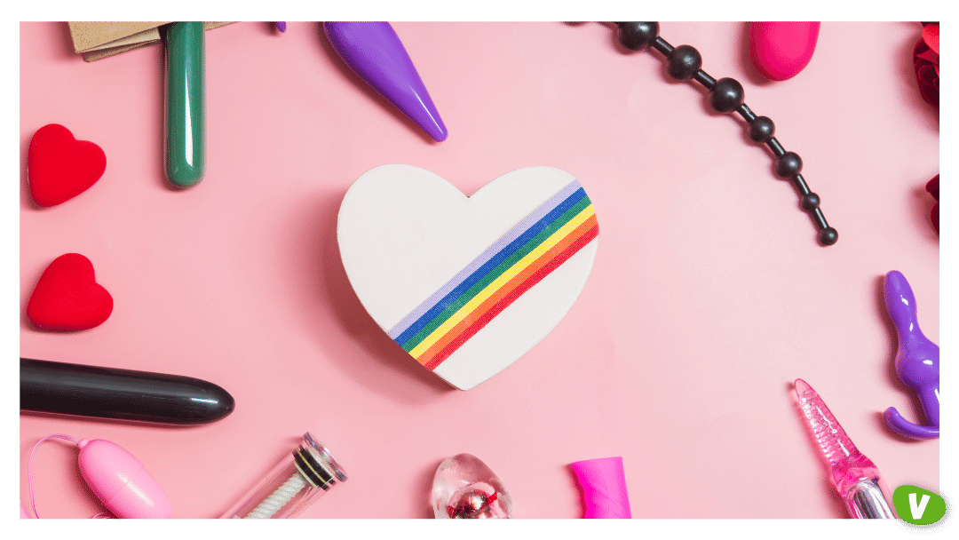 a white heart with lgbtq+ stripes on a pink background surrounded by a variety of sex toys