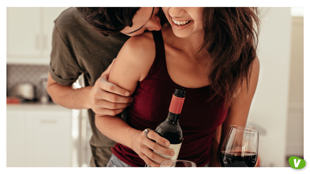 couple having date night, man holding a woman from the back while pouring wine, dating goals