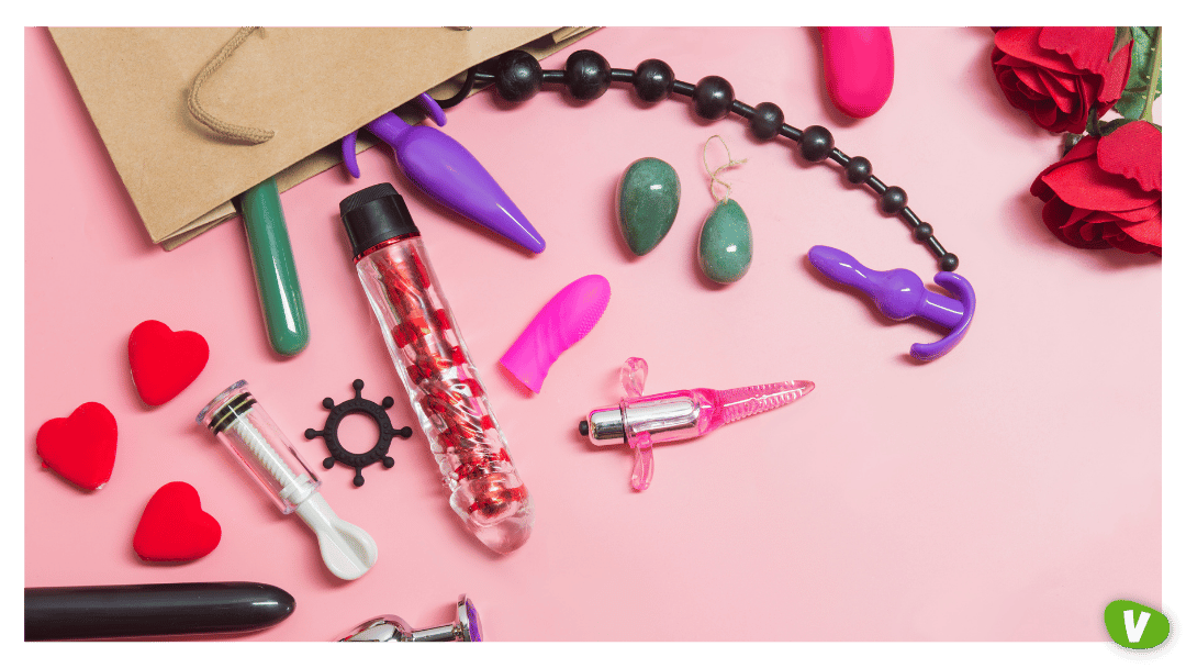 A variety of colourful sex toys and accessories, including vibrators, butt plugs, and jade eggs, displayed on a pink background with roses, promoting eco-friendly intimacy.