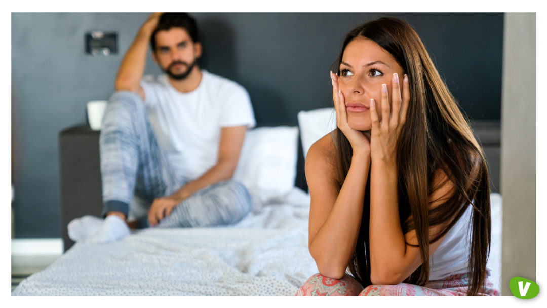 A woman sitting on the edge of the bed with her hands on her face, looking distressed, while a man sits in the background, depicting post sex anxiety, after escort session feelings, and the emotional challenges linked to paid intimacy emotions.