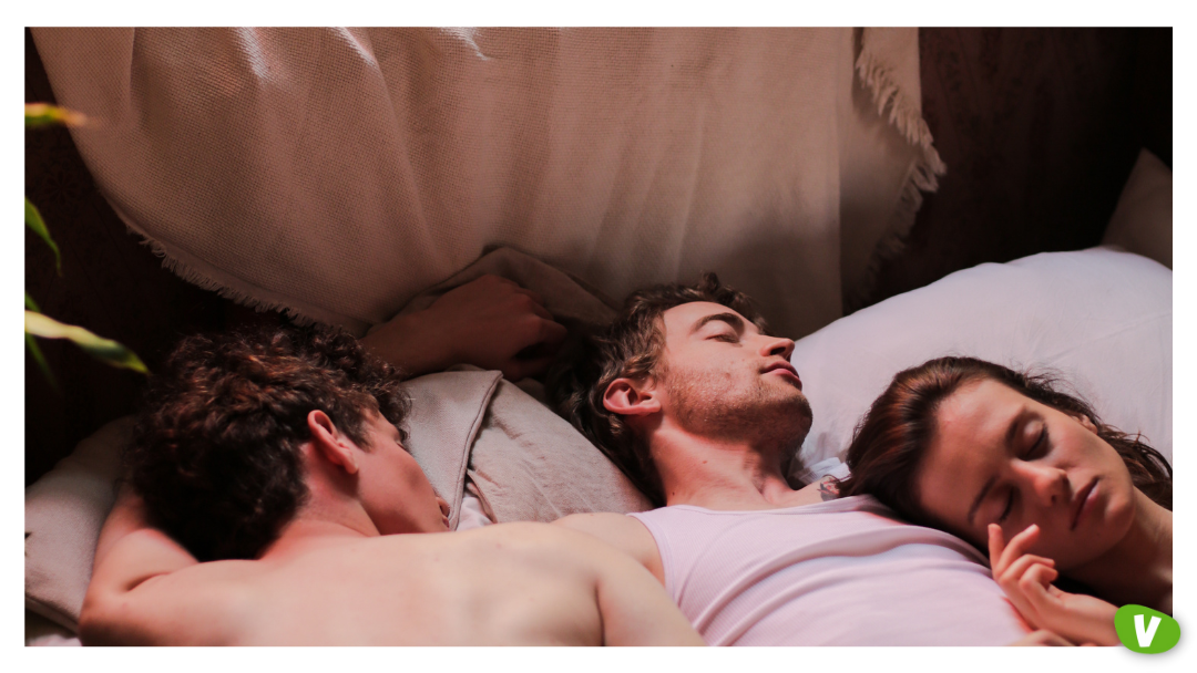Close-up of three people cuddling in bed, symbolizing a couple hiring an escort as a couple, showcasing intimacy and couple-friendly escort tips for a threesome with an escort.