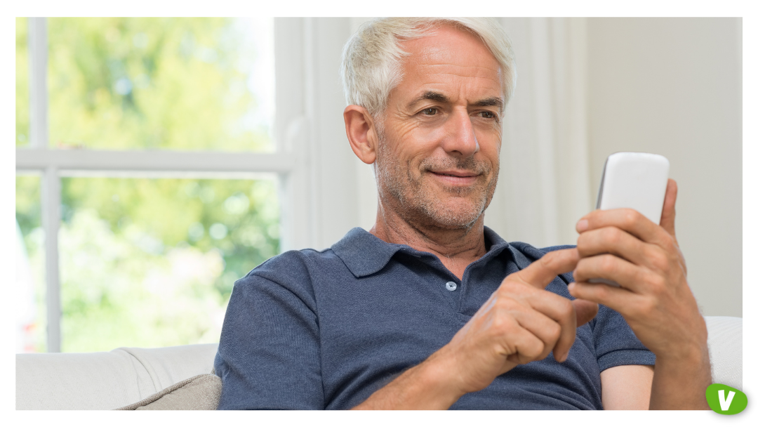 An older man smiling while using his phone indoors, reflecting escort timewasters and the importance of a timewaster checklist for avoiding bad clients and applying escorting tips UK.
