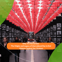 People walk beneath a canopy of red umbrellas suspended above a street lined with black-and-white portraits of individuals. A red London bus is visible in the distance. Overlaid text reads: “Why We Remember: The Origins and Legacy of International Day to End Violence Against Sex Workers.”